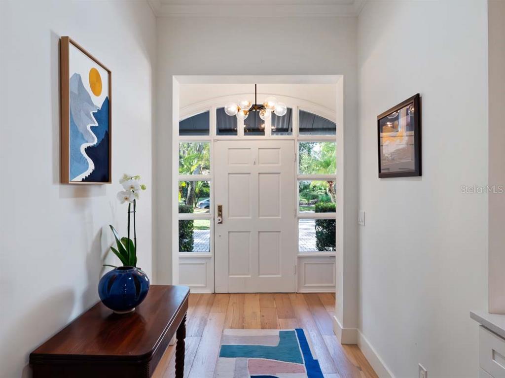 A bright entryway features a white front door, hardwood floors, and a console table — 10457 CROMWELL GROVE TERRACE, ORLANDO, FL