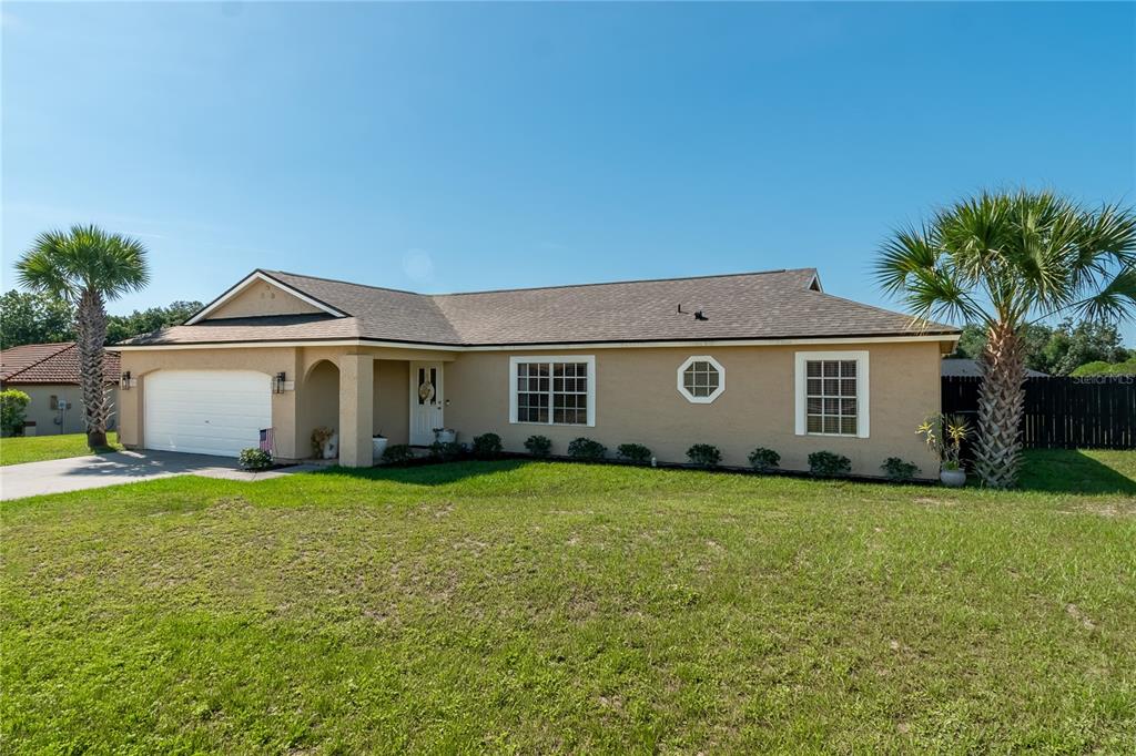 A single-story tan house with a two-car garage, a front porch, and two palm trees — 308 OAK LANE PASS, OCALA, FL