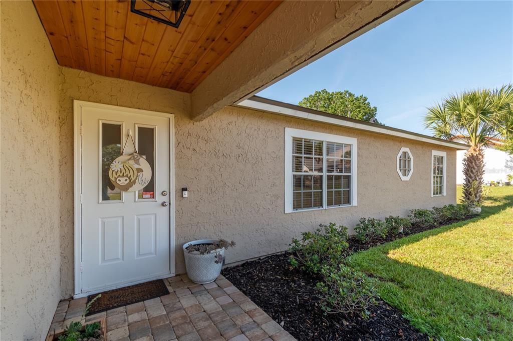 The exterior of a house features a white front door, a wood-paneled porch, and landscaping — 308 OAK LANE PASS, OCALA, FL