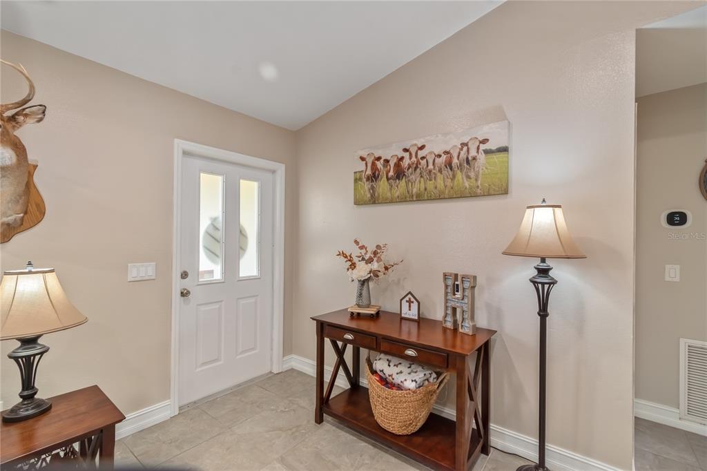 An entryway features a white front door, a wooden console table, and wall decor — 308 OAK LANE PASS, OCALA, FL