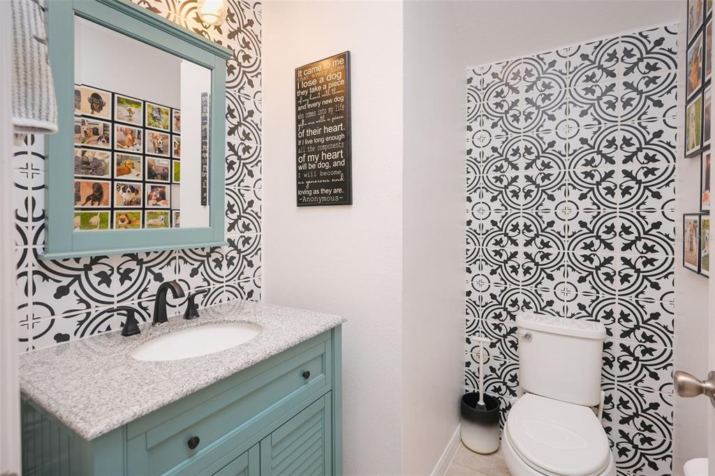 A bathroom features a teal vanity, granite countertop, and walls with black and white patterned wallpaper — 31300 KALE BROOKS COURT, SAN ANTONIO, FL