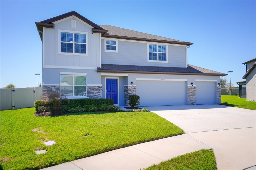 A two-story house with light blue siding, a stone facade, and a three-car garage — 31300 KALE BROOKS COURT, SAN ANTONIO, FL