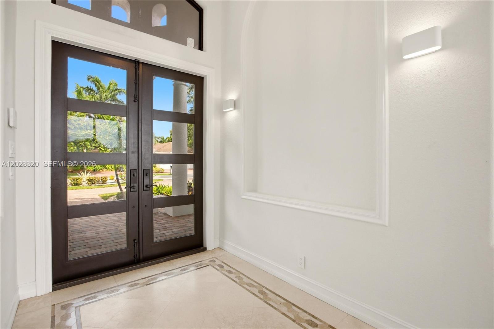 An entryway features double glass-paneled doors, a tiled floor with a border, and wall sconces — 3250 W Stonebrook Cir, Davie FL 33330, DAVIE, FL