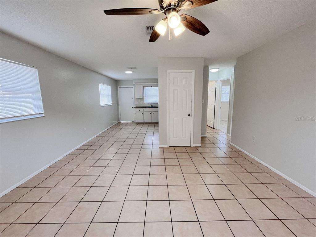 An open-concept living area features light-colored tile flooring, gray walls, and a ceiling fan — 5723 SILVER SPUR DRIVE, HOLIDAY, FL