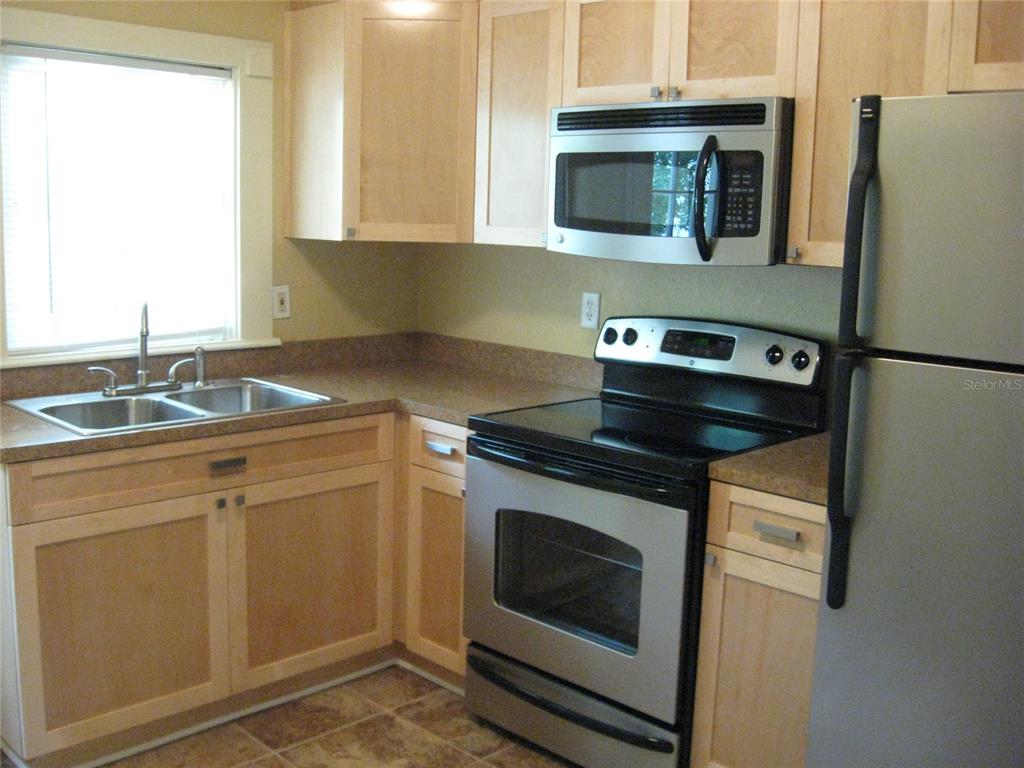 A kitchen features light wood cabinets, stainless steel appliances, and a double basin sink — 1506 N 15TH STREET, TAMPA, FL