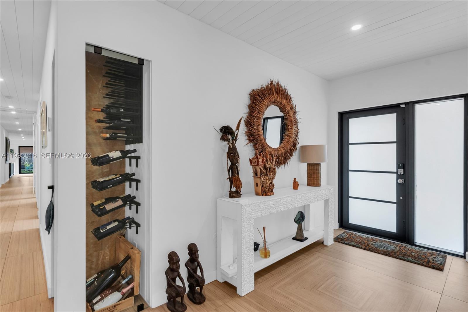 An entryway features a white console table, a wall-mounted wine rack, and a glass-paneled door — 2025 Arch Creek Dr, North Miami FL 33181, NORTH MIAMI, FL