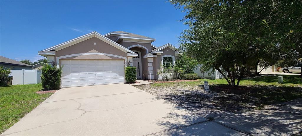 A single-story house with a beige stucco exterior, a two-car garage, and a concrete driveway — 3109 TURNBERRY BOULEVARD, KISSIMMEE, FL