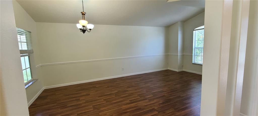 An empty dining room features wood-look flooring, a chandelier, and white chair rail molding — 3109 TURNBERRY BOULEVARD, KISSIMMEE, FL