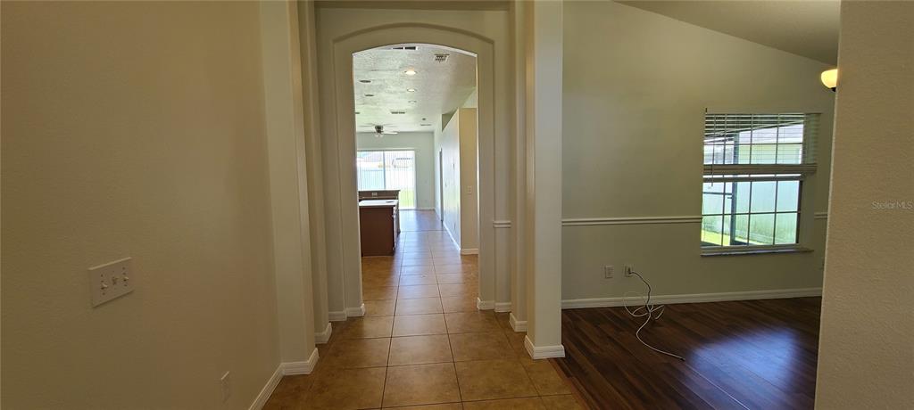 A tiled hallway leads to a kitchen, with a dining area featuring wood flooring nearby — 3109 TURNBERRY BOULEVARD, KISSIMMEE, FL