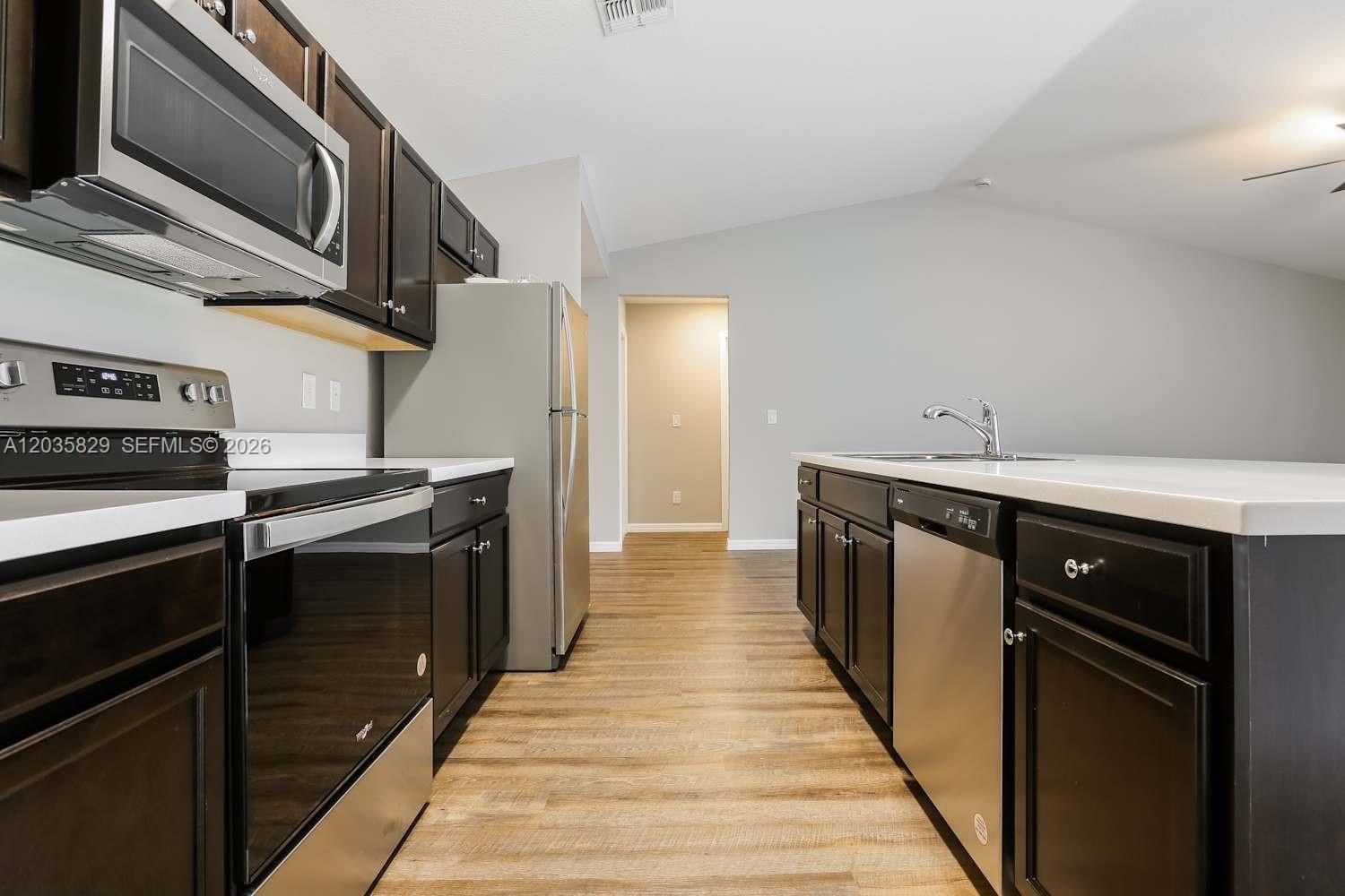 A kitchen features dark wood cabinets, stainless steel appliances, and light countertops — PORT ST. LUCIE, FL
