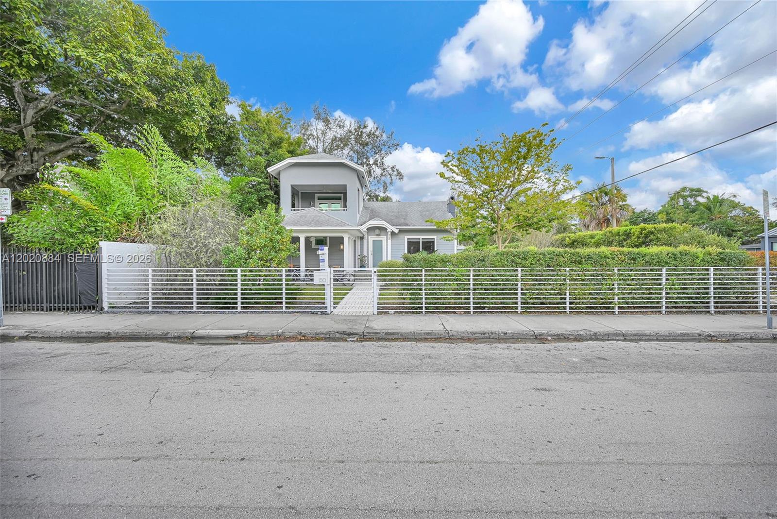 A two-story gray house with a white fence stands behind a sidewalk and street — 150 NE 50th Ter, Miami FL 33137, MIAMI, FL
