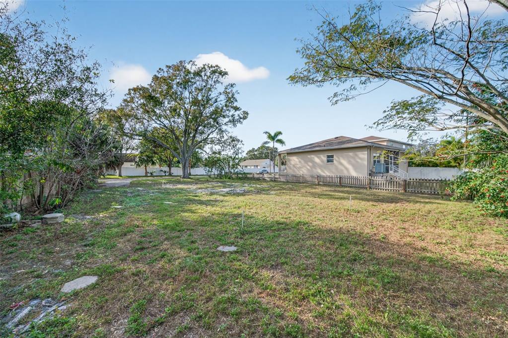A vacant, grassy residential lot with a wooden fence and a house in the background — 6311 HOBSON STREET NE, ST PETERSBURG, FL