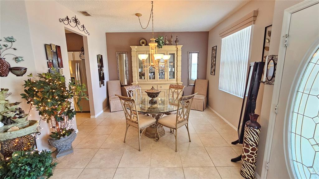 A dining room features a glass-topped table, a large hutch, and tile flooring — 543 TERRANOVA CIRCLE, WINTER HAVEN, FL