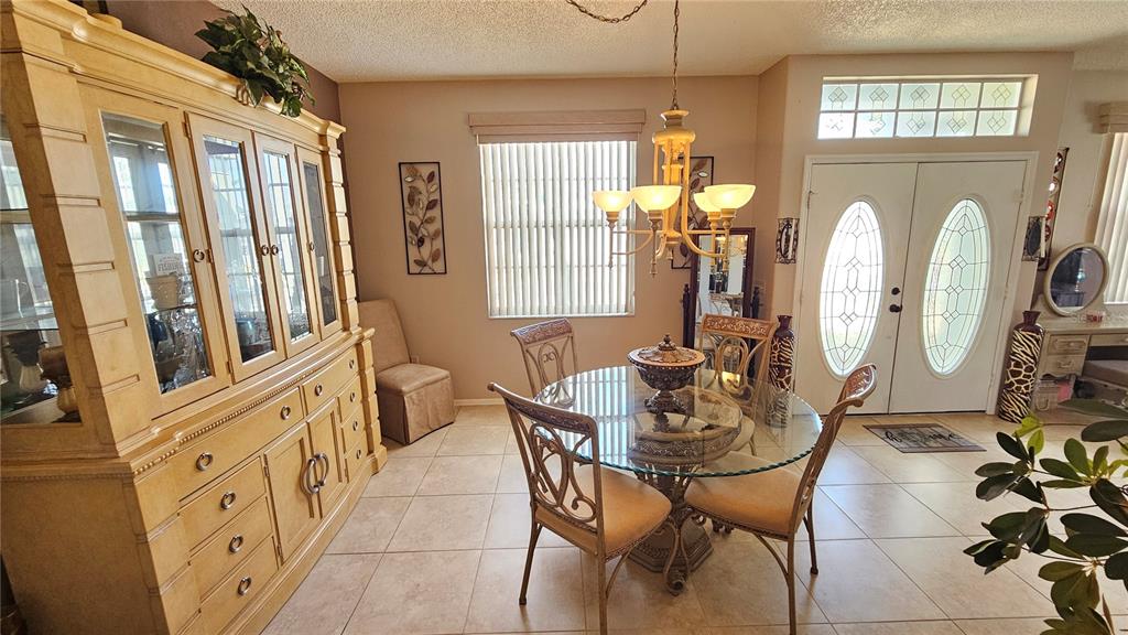 A dining room features a glass-topped table, metal chairs, a large hutch, and double entry doors — 543 TERRANOVA CIRCLE, WINTER HAVEN, FL