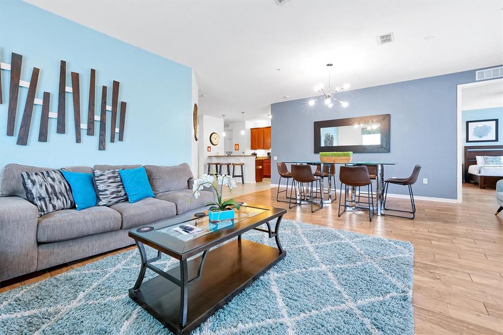 A living room and dining area feature light blue walls, wood flooring, and modern furniture — 4840 CAYVIEW AVENUE UNIT 20310, ORLANDO, FL