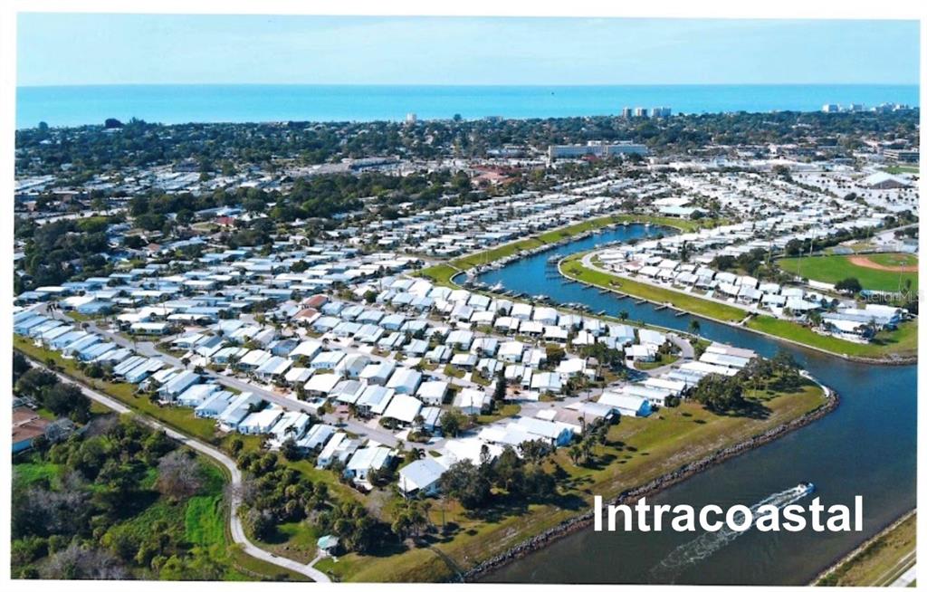 An aerial view shows a residential community of manufactured homes situated along a waterway — 857 S GREEN CIRCLE, VENICE, FL