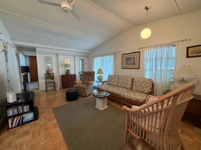 A living room features a patterned sofa, a wicker chair, and light wood parquet flooring — 857 S GREEN CIRCLE, VENICE, FL