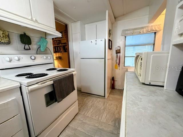 A kitchen features white cabinets, a white stove, a refrigerator, and a microwave on counters — 857 S GREEN CIRCLE, VENICE, FL