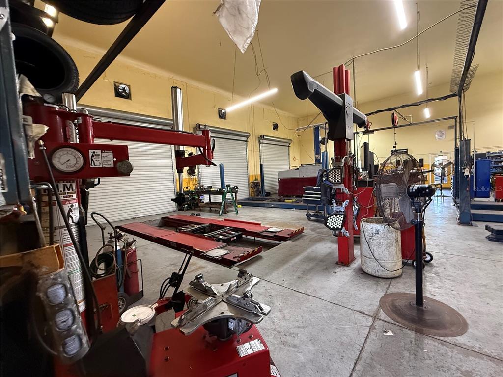 An auto repair shop interior features vehicle lifts, tire changing equipment, and a large fan — 23371 HARBORVIEW ROAD UNIT A, PUNTA GORDA, FL