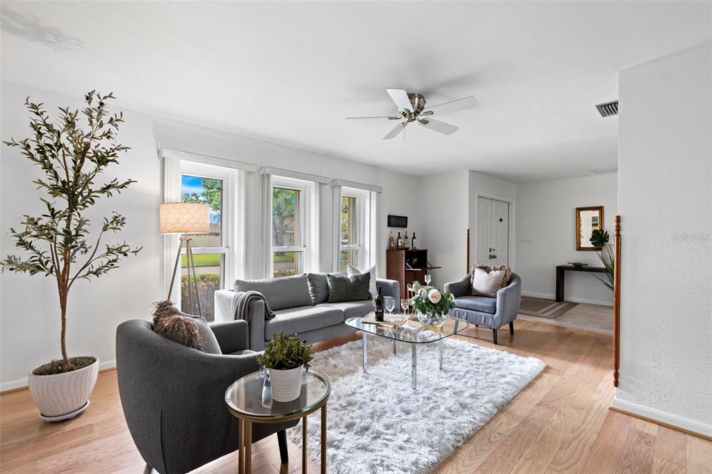 A living room features a gray sofa, two armchairs, a glass coffee table, and hardwood floors — 511 RIVIERA BAY DRIVE NE, ST PETERSBURG, FL