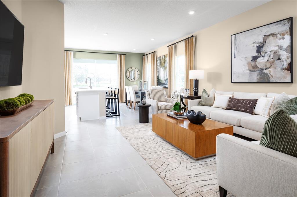 A living room with a white sofa, wooden coffee table, and an adjacent kitchen area — 12542 AMBER CREEK CIRCLE, LAKEWOOD RANCH, FL