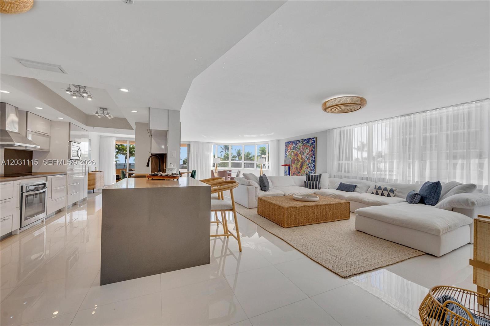 A modern open-concept living area features a kitchen with a large island and white cabinetry — 10175 Collins Ave # 102, Bal Harbour FL 33154, BAL HARBOUR, FL