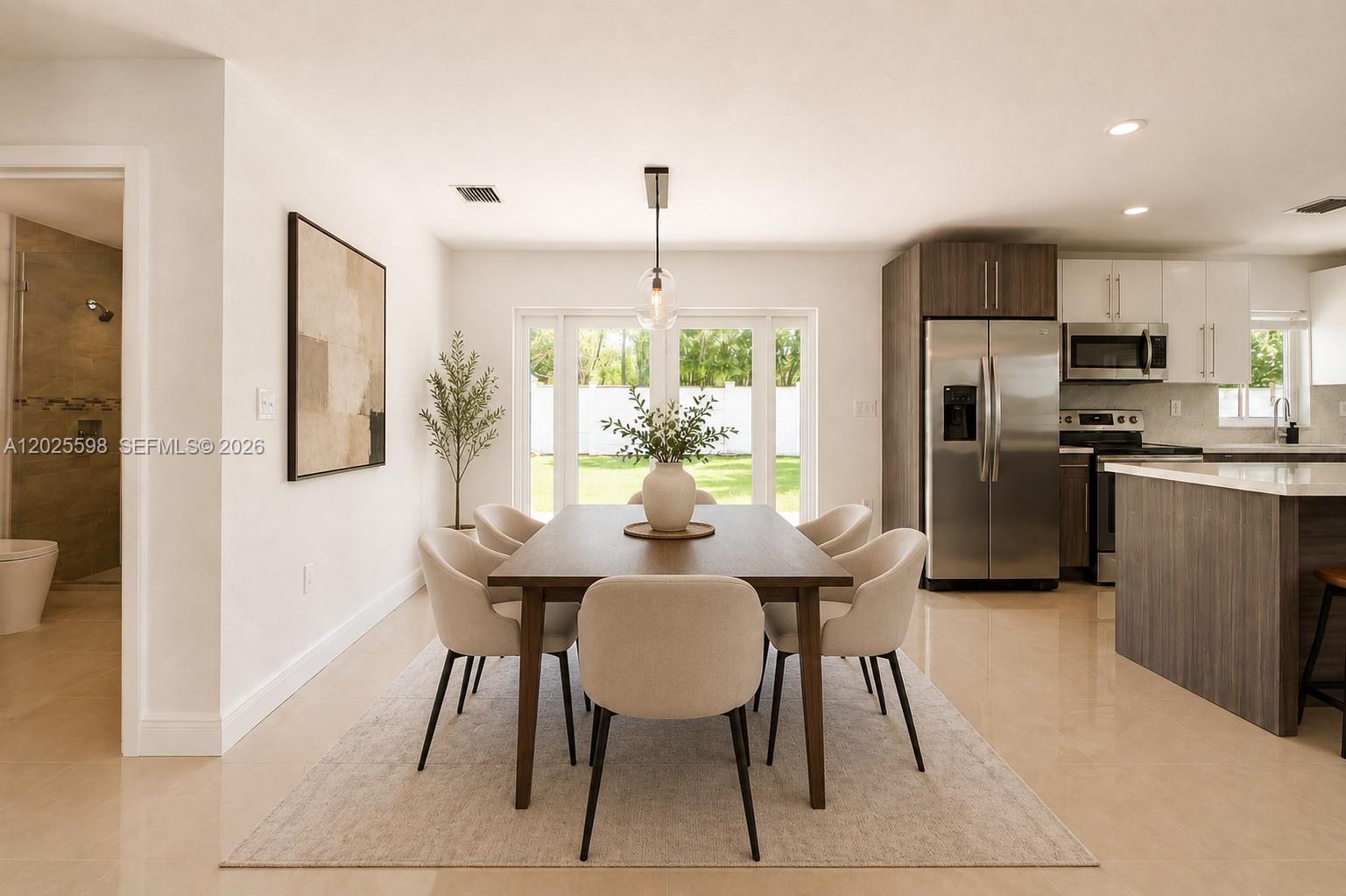 A dining area features a wooden table, six chairs, and a pendant light near a kitchen — 9421 SW 150th St, Miami FL 33176, MIAMI, FL