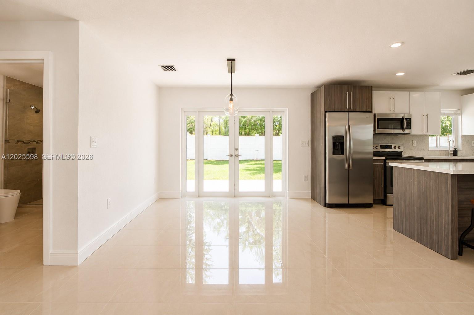 A bright, open-concept kitchen and dining area features white walls, tile flooring, and glass doors — 9421 SW 150th St, Miami FL 33176, MIAMI, FL