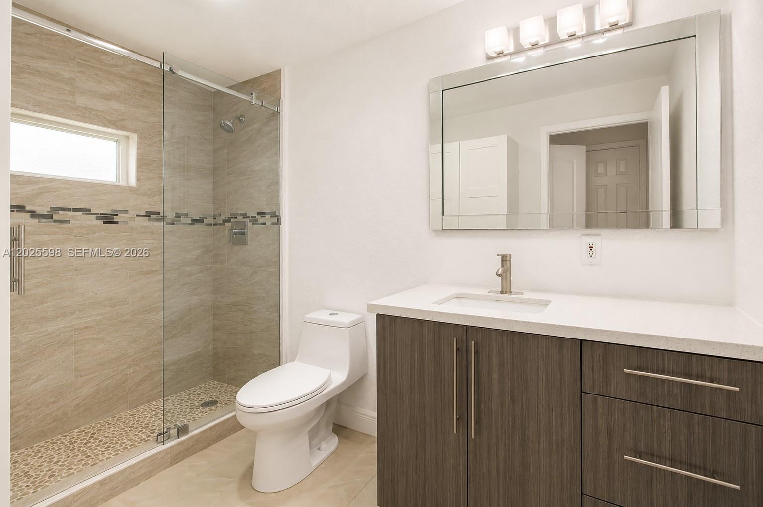 A modern bathroom features a glass-enclosed shower, a white toilet, and a dark wood vanity — 9421 SW 150th St, Miami FL 33176, MIAMI, FL