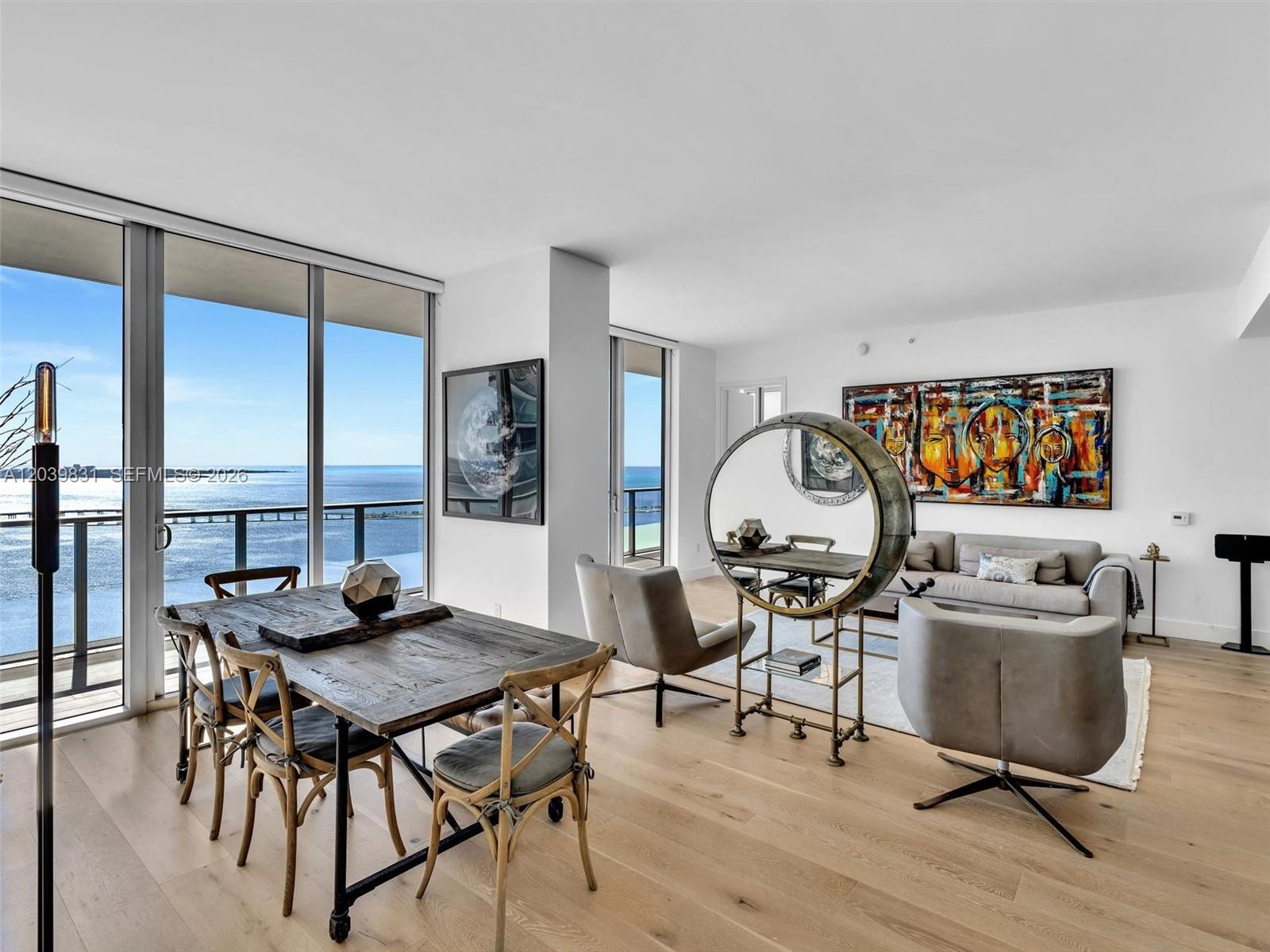 A modern living and dining area with floor-to-ceiling windows overlooking the ocean — 1300 E Brickell Bay Dr # 4202, Miami FL 33131, MIAMI, FL