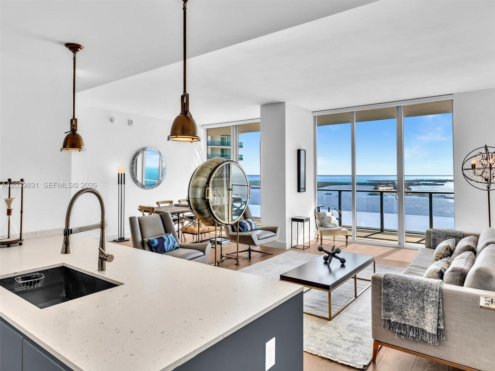 A modern open-concept living area features a kitchen island, dining space, and floor-to-ceiling ocean views — 1300 E Brickell Bay Dr # 4202, Miami FL 33131, MIAMI, FL