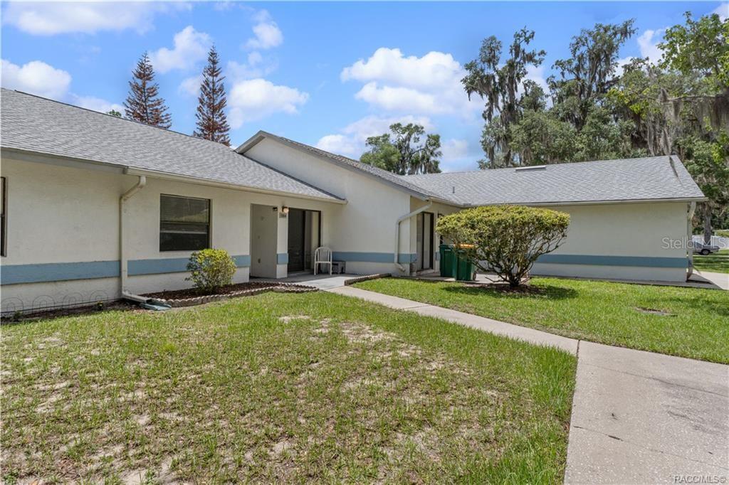A single-story building with a light-colored exterior, a gray shingled roof, and a concrete walkway — 1304 SIESTA TERRACE UNIT 1304, INVERNESS, FL
