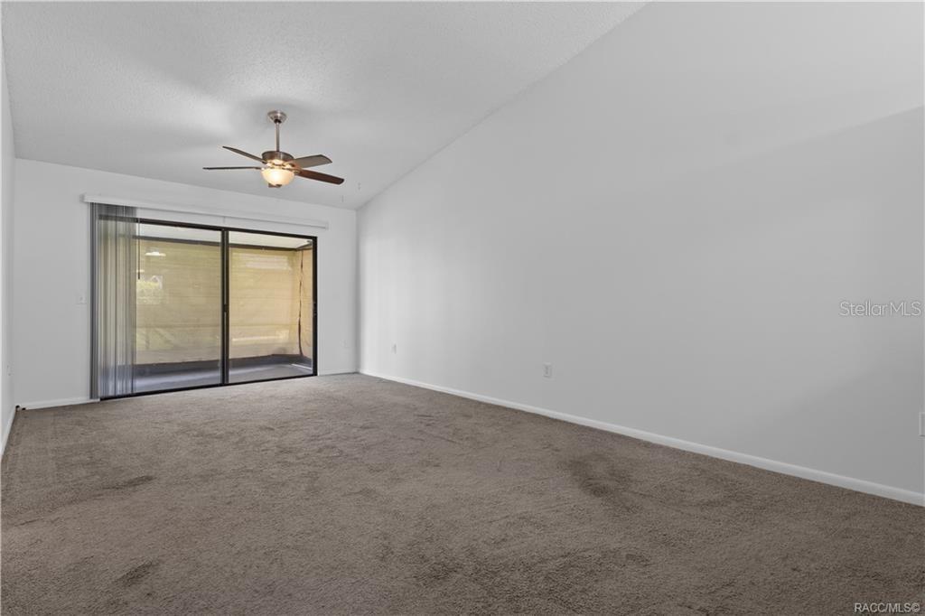 An empty room with gray carpet, white walls, a ceiling fan, and sliding glass doors — 1304 SIESTA TERRACE UNIT 1304, INVERNESS, FL