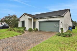 A single-story house with a two-car garage and a paved driveway under a blue sky — 163 KENNY BOULEVARD, HAINES CITY, FL