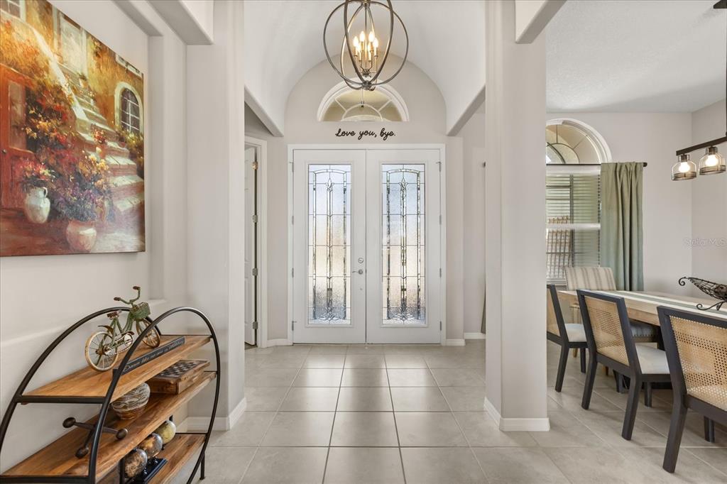 A bright entryway features tiled floors, a vaulted ceiling, and double glass-paneled front doors — 2472 PAWTUCKET PASS, MOUNT DORA, FL