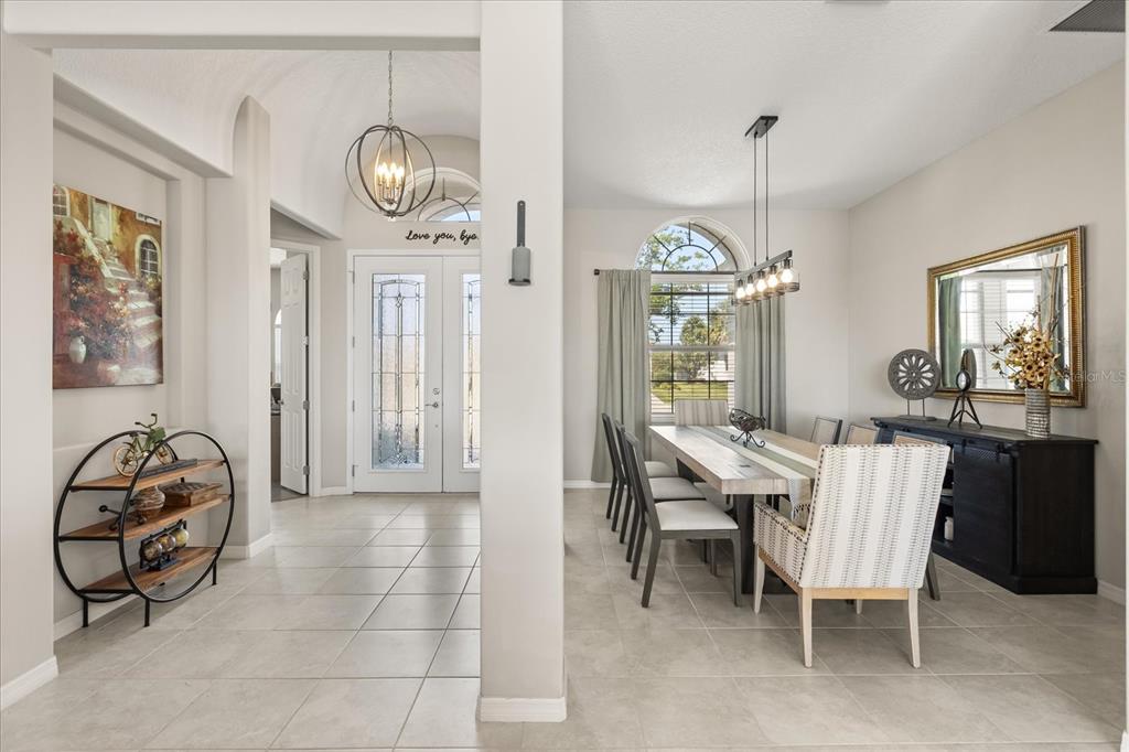 A dining room with a long table and a foyer with a circular shelf — 2472 PAWTUCKET PASS, MOUNT DORA, FL
