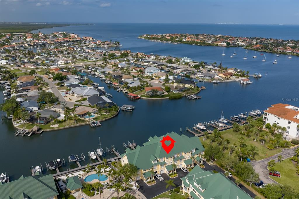 An aerial view shows a waterfront condominium complex with boat slips and a swimming pool — 6432 SUNSET BAY CIRCLE, APOLLO BEACH, FL