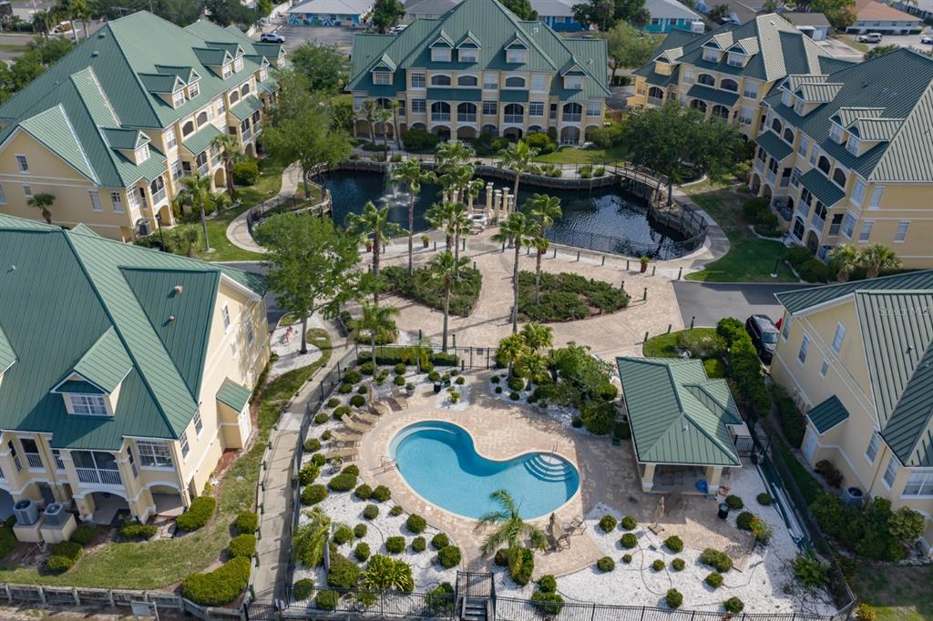 An aerial view of a multi-story apartment complex featuring a central pond and swimming pool — 6432 SUNSET BAY CIRCLE, APOLLO BEACH, FL