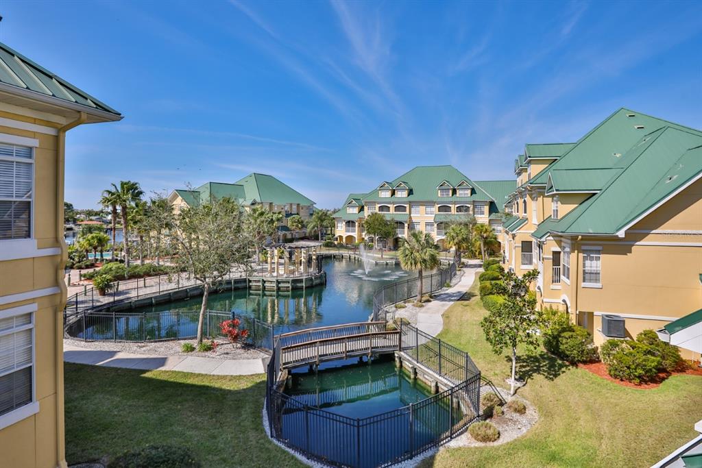 An exterior view of apartment buildings surrounding a central pond with a pedestrian bridge — 6432 SUNSET BAY CIRCLE, APOLLO BEACH, FL