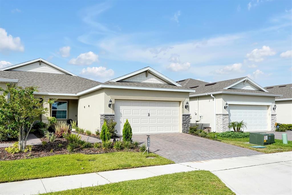 A street-level view of two adjacent single-story suburban homes with attached garages and driveways — 2726 SUMMER RETREAT LANE, KISSIMMEE, FL
