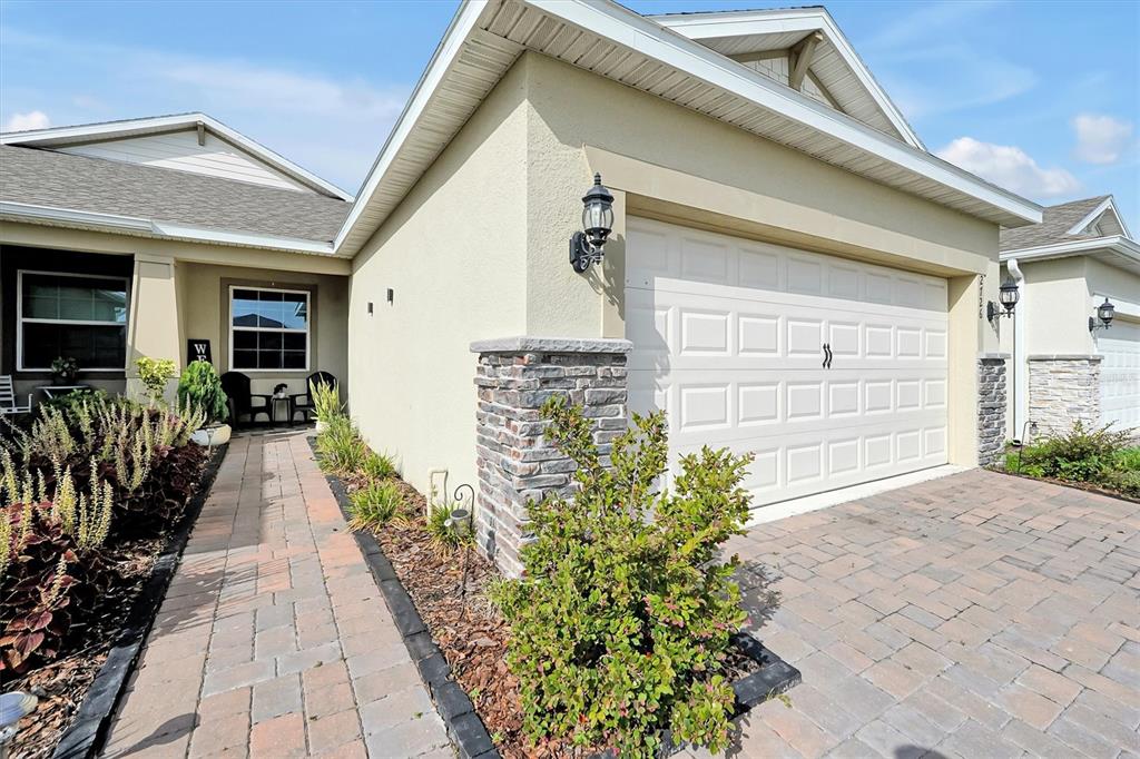 A paved walkway leads to the entrance of a house with a stone-accented garage — 2726 SUMMER RETREAT LANE, KISSIMMEE, FL
