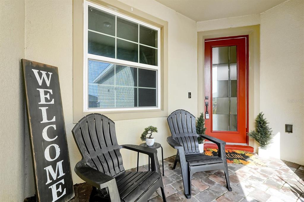 A front porch features two black chairs, a welcome sign, and a red front door — 2726 SUMMER RETREAT LANE, KISSIMMEE, FL