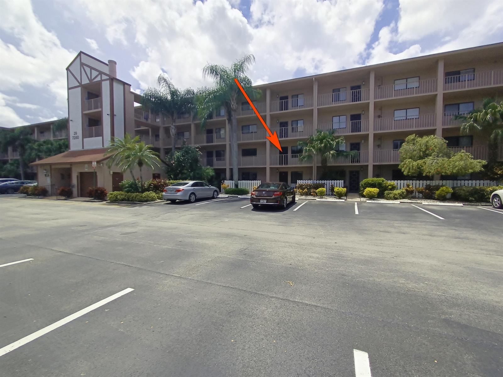 An exterior view of a multi-story apartment building with a parking lot in front — 7280 Amberly Lane # 207, Delray Beach FL 33446, DELRAY BEACH, FL