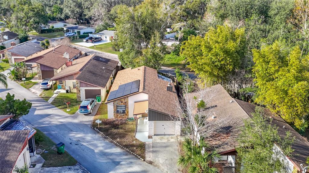 An aerial view shows several suburban houses with shingled roofs, driveways, and surrounding trees — 5937 FOREST LANE, ZEPHYRHILLS, FL
