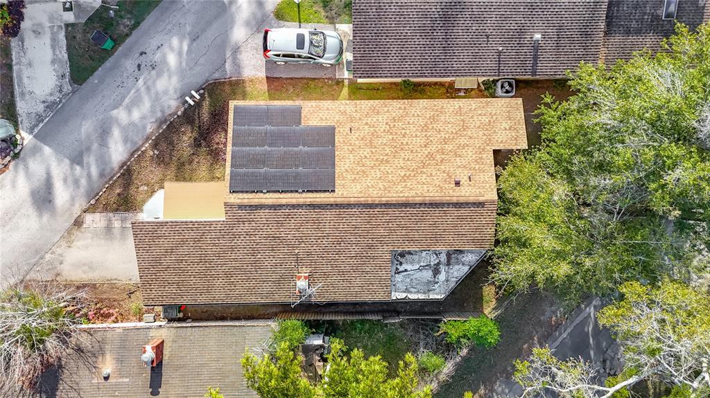 An aerial view shows a house roof with solar panels and a flat section — 5937 FOREST LANE, ZEPHYRHILLS, FL