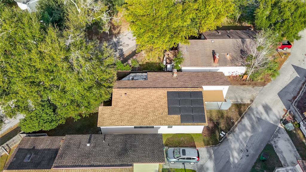 An aerial view shows a house with solar panels on its roof and a parked car — 5937 FOREST LANE, ZEPHYRHILLS, FL