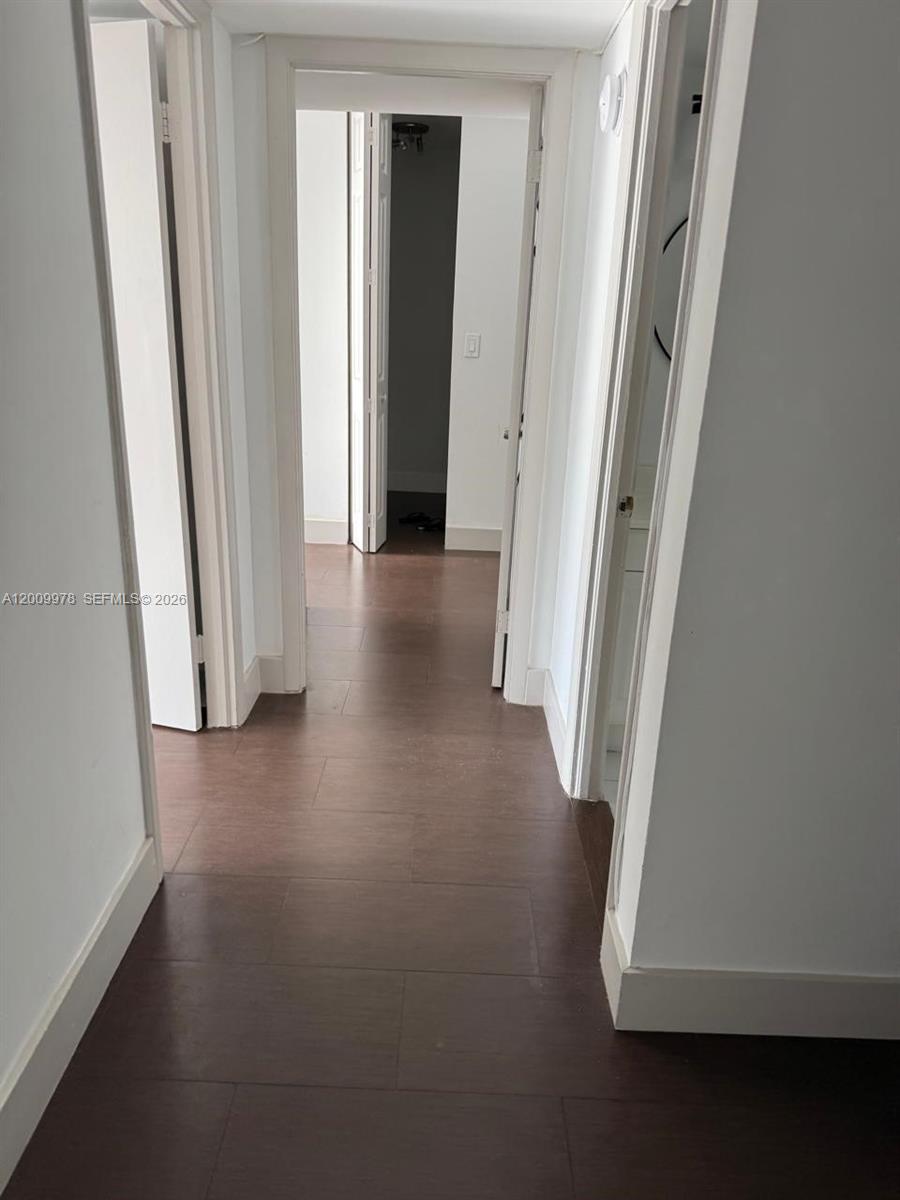 A hallway with dark wood-look flooring leads to an open doorway in the distance — 150 Ocean Lane Dr # 6F, Key Biscayne FL 33149, KEY BISCAYNE, FL