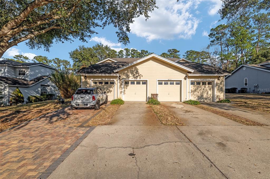 A duplex with light yellow siding, two garage doors, and a paved driveway — 3615 NW 104TH DRIVE UNIT 102, GAINESVILLE, FL