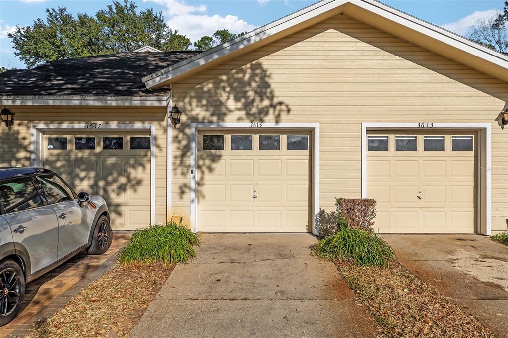 A beige exterior view shows three garage doors with windows and a parked car — 3615 NW 104TH DRIVE UNIT 102, GAINESVILLE, FL