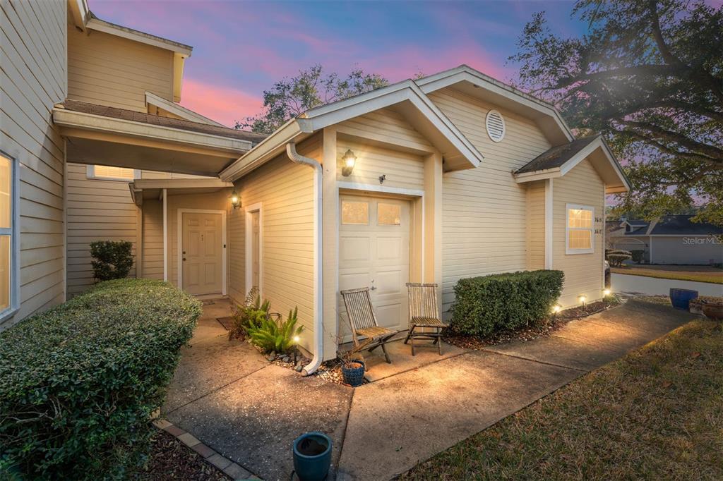 The exterior of a tan house features a covered entryway, a garage door, and landscaping — 3615 NW 104TH DRIVE UNIT 102, GAINESVILLE, FL